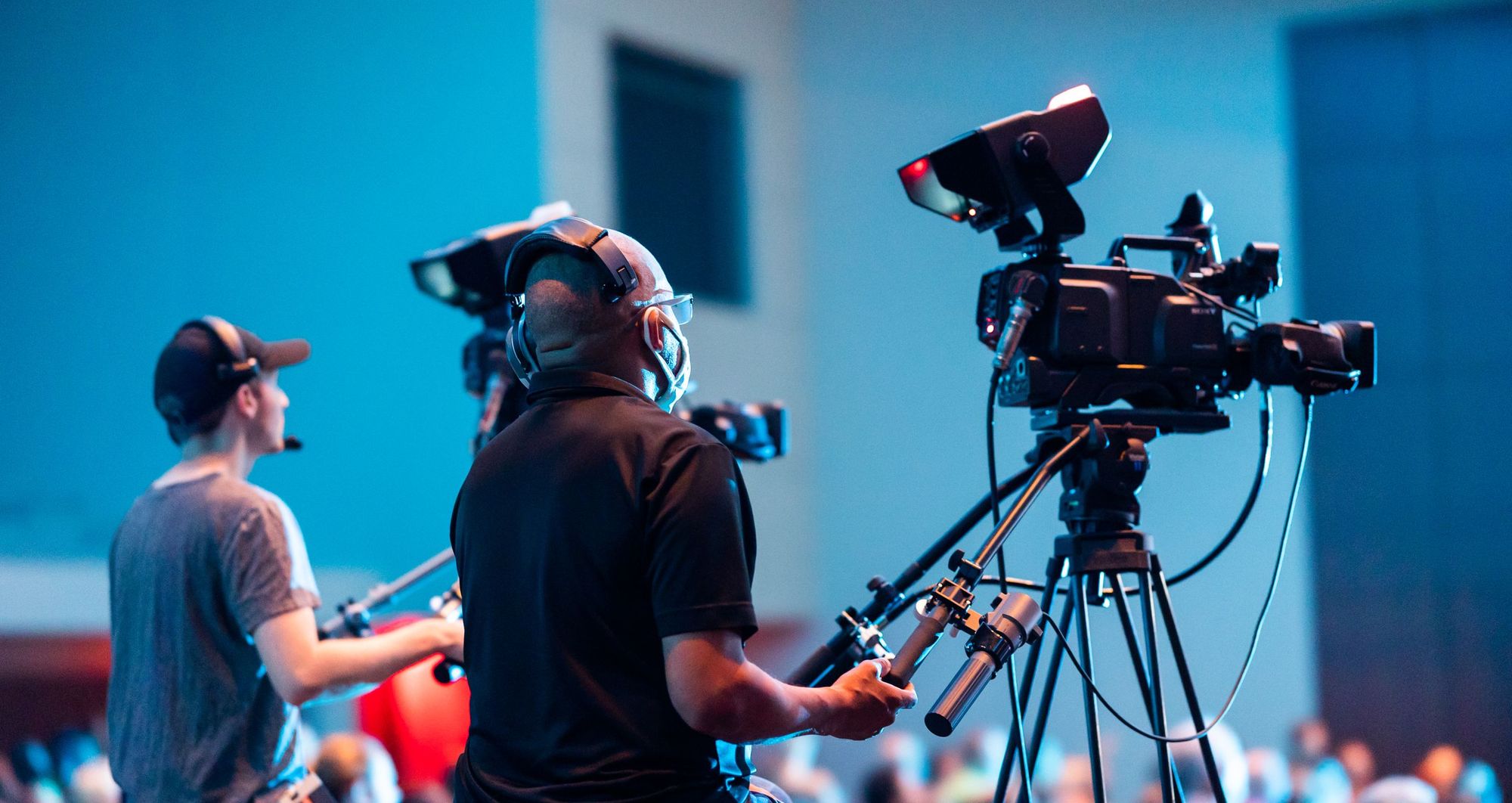 Camera operators filming a live event with broadcast cameras on tripods