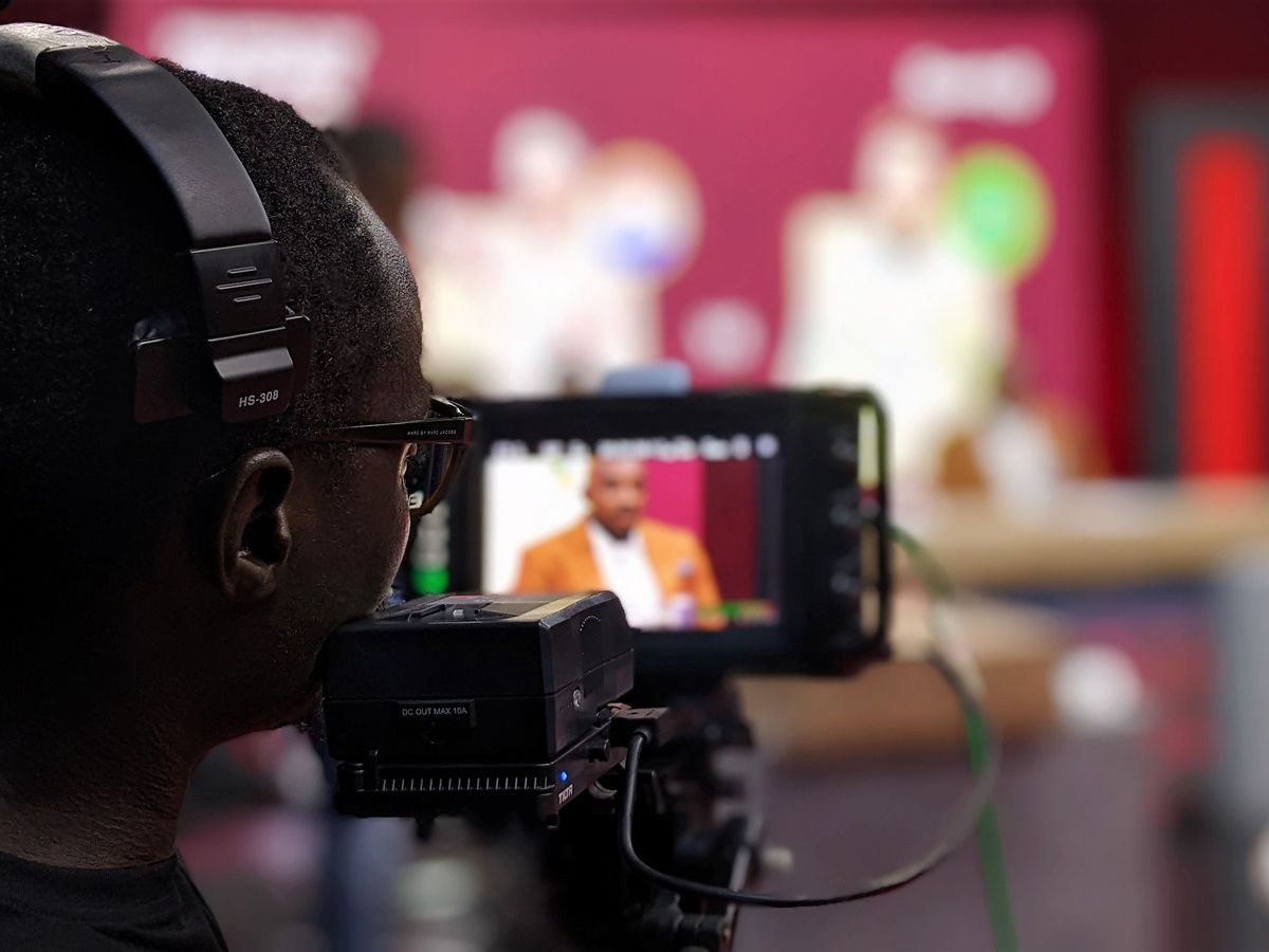 Camera operator wearing an intercom headset while filming a studio presenter