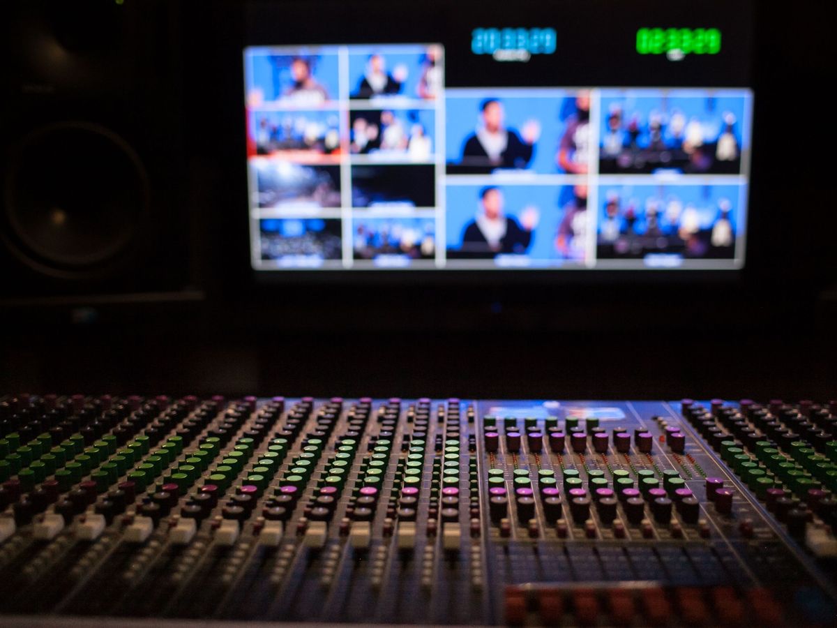 Multiviewer monitor wall above a mixing console in a broadcast control room