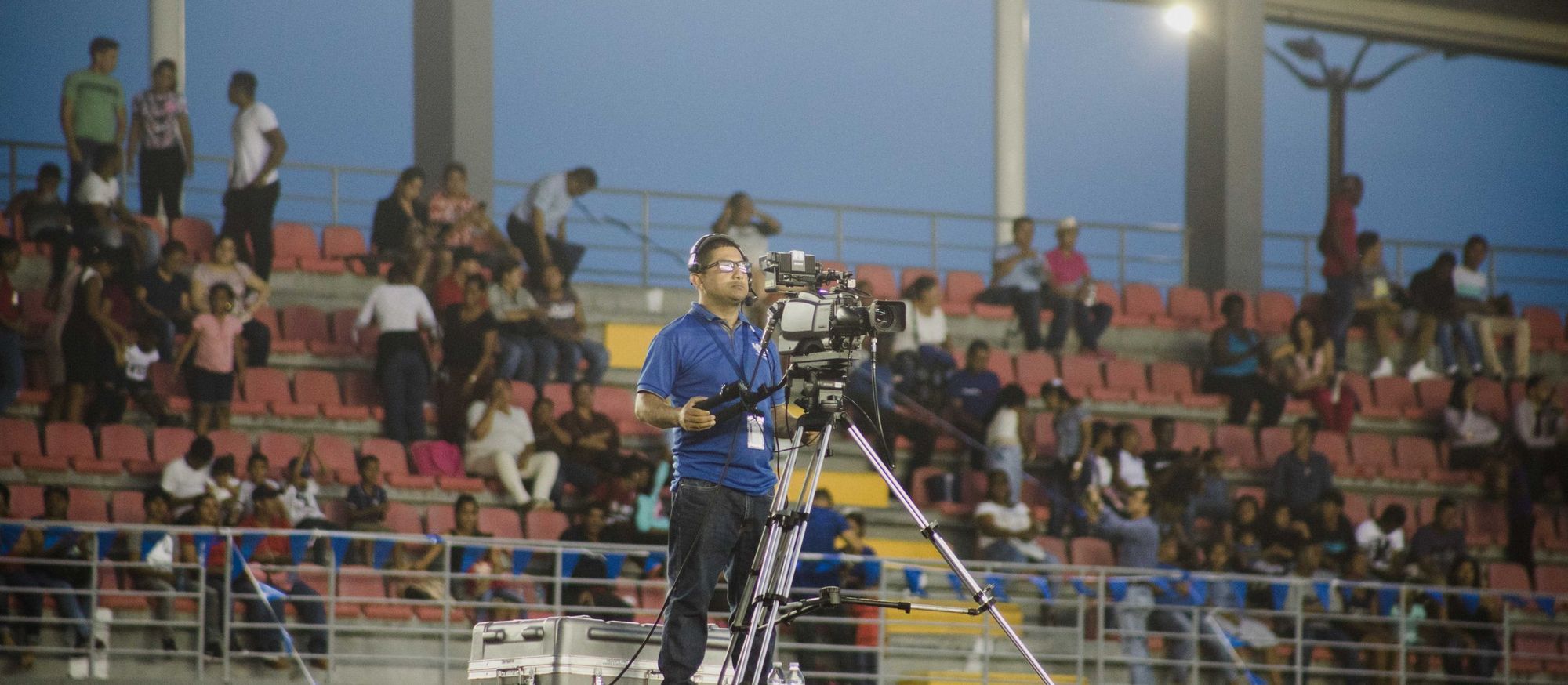 Camera operator filming a live event from a stadium stand